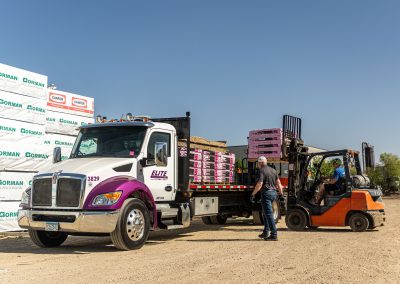 Elite Transportation Systems flatbed truck taking on palletized building materials from a yard forklift