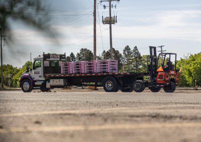 Elite Transportation Systems flatbed loaded with palletized insulation as an driver backs the forklift away