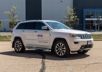 Elite Transportation Systems Jeep Grand Cherokee courier vehicle parked outside a commercial building