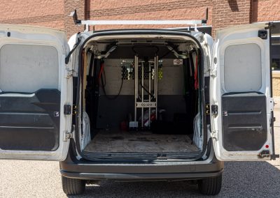 Rear doors open on an Elite Transportation Systems small cargo van showing the cargo bay and rack