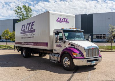 Elite Transportation Systems 26-foot dock truck parked outside a commercial building on a sunny afternoon