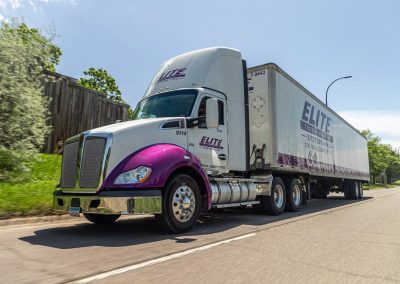 Elite Transportation Systems Kenworth semi hauling a 53-foot dry van down a road, shot in motion from the driver side