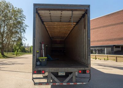 Open rear doors of an Elite 53-foot dry van trailer showing the empty wood deck, pallet jack, and hand truck
