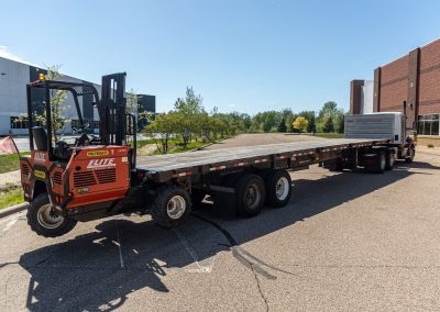 Elite Transportation Systems semi flatbed with a Palfinger piggyback forklift mounted on the rear of the empty deck